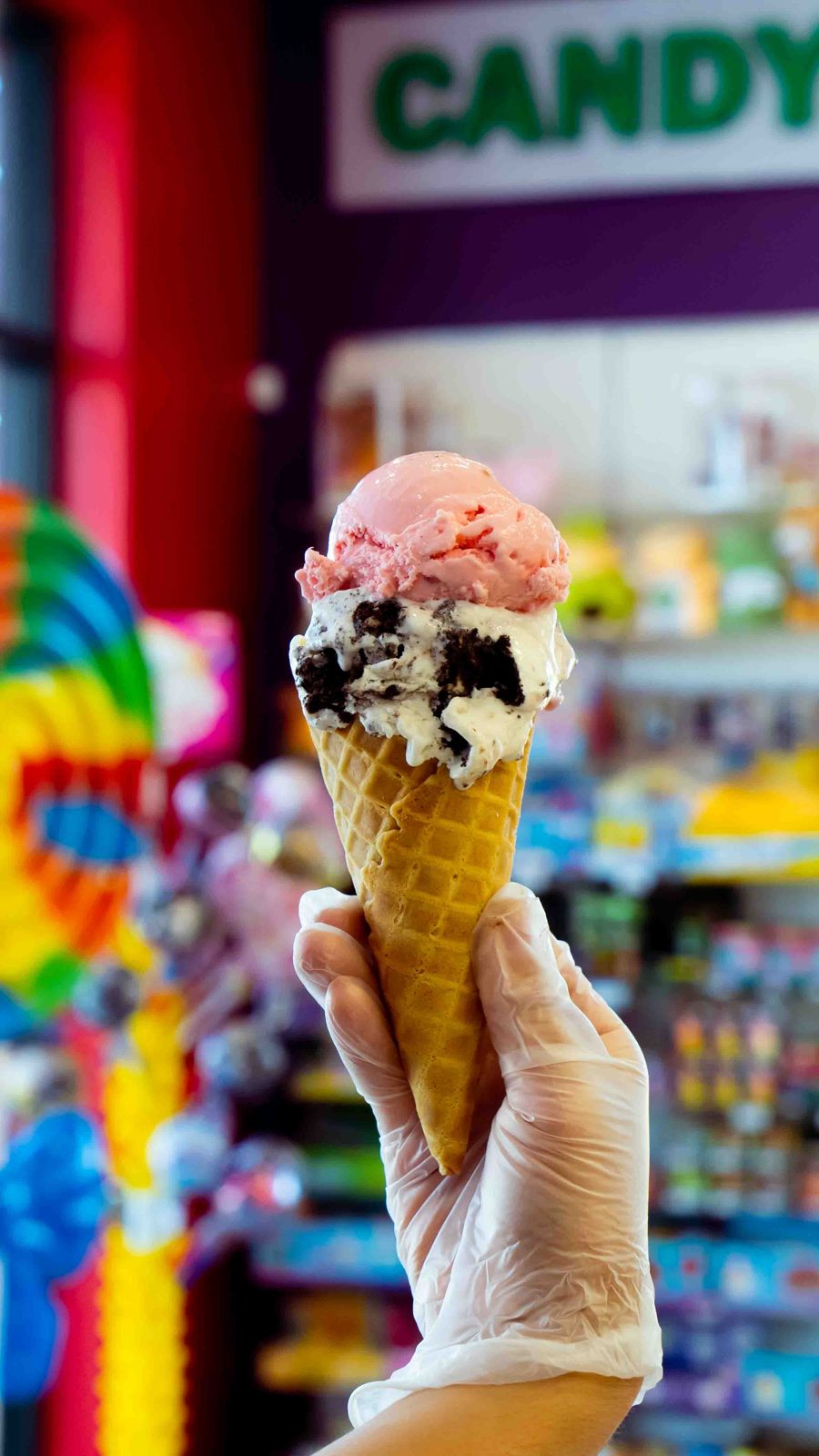 Hand holding a two-scoop ice cream waffle cone in the candy store